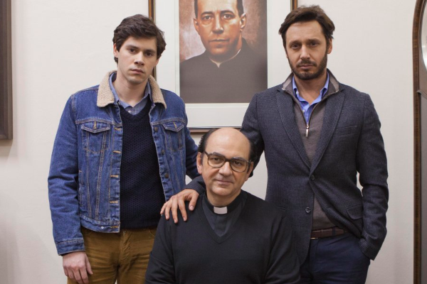 Pedro Campos (Thomas Leyton joven), Benjamín Vicuña (Thomas Leyton adulto) y Luis Gnecco (Fernando Karadima) posan frente a un retrato del verdadero Karadima.