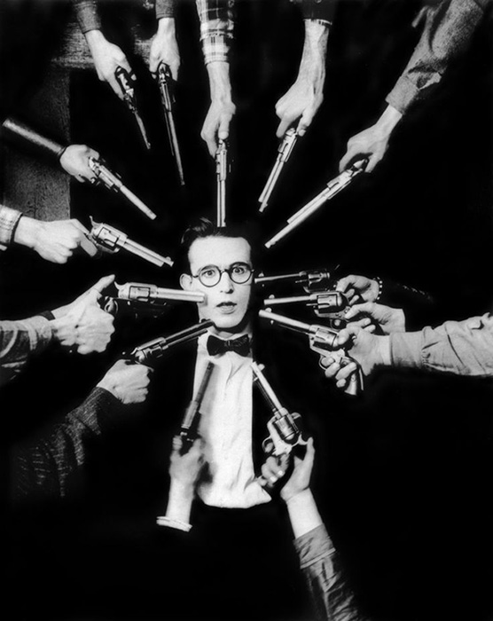 1920: American comedian and actor Harold Lloyd (1893-1971) looks surprised while fourteen pistols are pointed at his head in a still from director Hal Roach's film, 'An Eastern Westerner'.