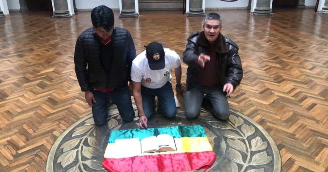 Camacho entra a Palacio, quita la wiphala y le pone la Biblia encima a la bandera de Bolivia. Foto: Piedad Córdoba/Twitter